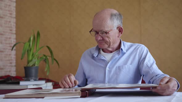 Cheerful Elderly Man Enjoying Memory of Family Photo Album, Watching Old Photos