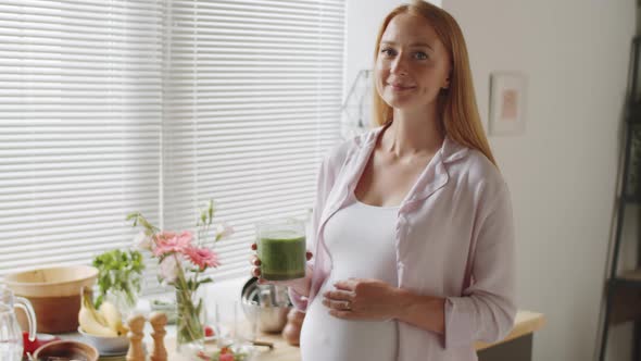 Positive Pregnant Woman Holding Smoothie and Posing for Camera