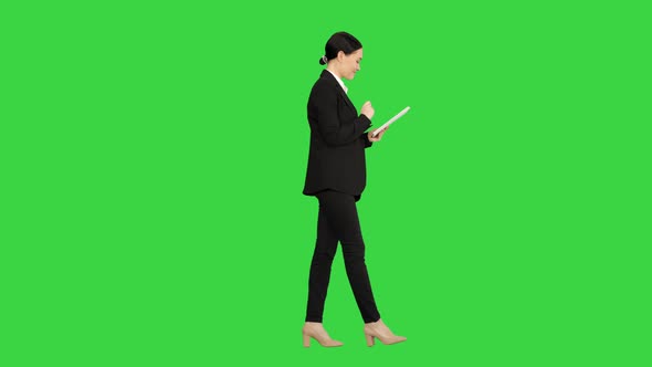 Smiling Businesswoman Using Computer Pad While Walking Towards the Camera on a Green Screen, Chroma