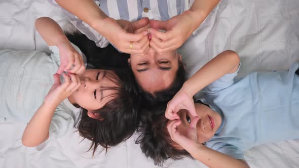 Top view portrait of Happy children playing with their mother lying on a bed at home.