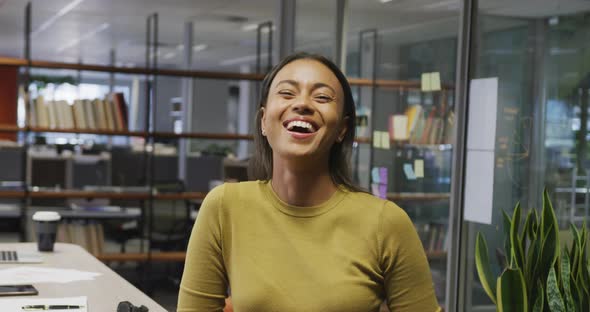 Portrait of happy biracial businesswoman in empty office