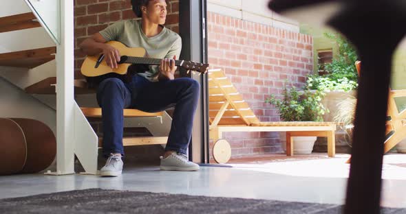 Happy african american man plays guitar and singing at home