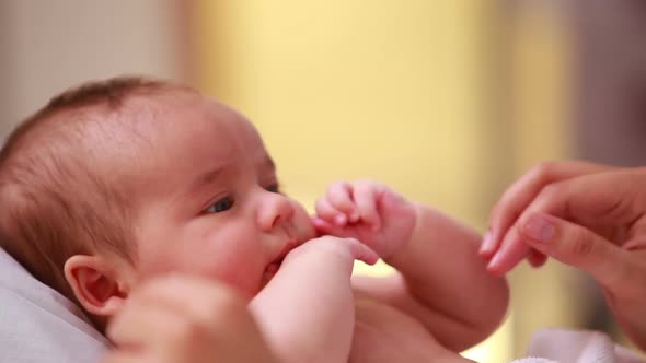 New born baby lying on a bed with the hand of an adult