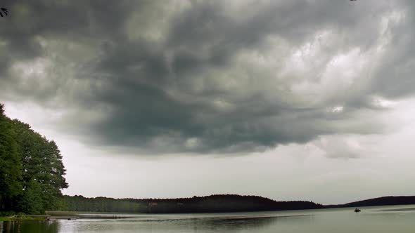 Calm summer landscape of forest lake. Heavy clouds.