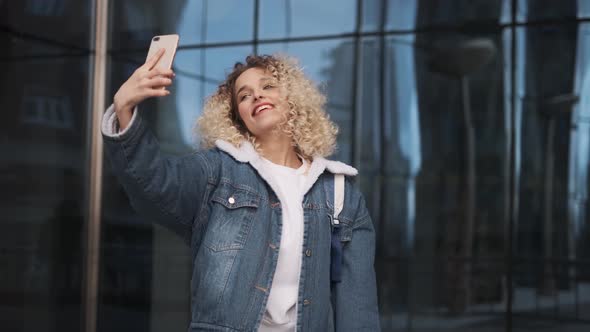 Beautiful Curly Girl Makes Selfie. Portrait of a Girl with a Charming Smile That Shoots Itself on