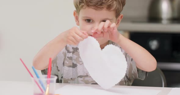 Close Up of a Little Boy's Who Just Cut and Draw a Red Heart with Watercolors and Present It to