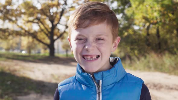 Happy Little Boy Smiling Without Front Baby Tooth on Sunny Autumn Day