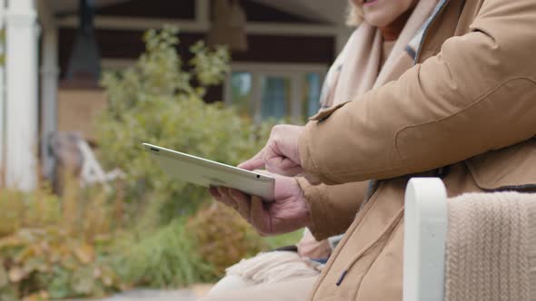 Unrecognizable Senior Couple Using Tablet Outdoors