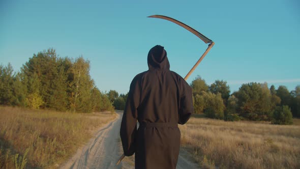 Scary Grim Reaper Walking on Dirt Road at Sunset