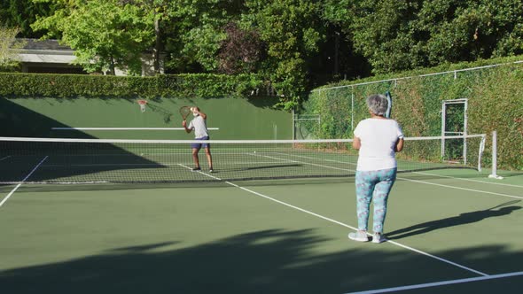 African american senior couple playing tennis on the tennis court on a bright sunny day