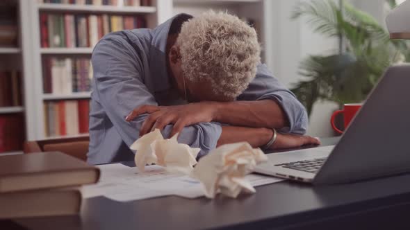 African American Man Put Head on Working Table with Laptop Due to Overwork