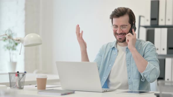 Young Man Laptop Talking Smartphone