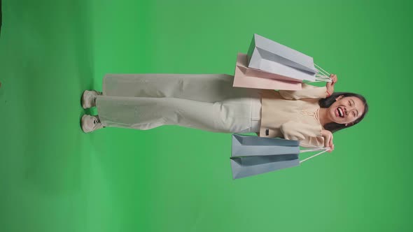 Full View Of An Asian Shopping Woman Holding Shopping Bags Up And Smile On Green Screen