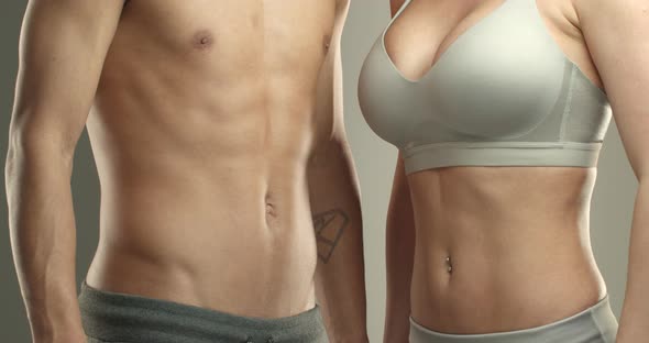 Closeup of Two Athletes Showing Abs Mascular Sportsman and Sportswoman Bump Fists Ready for Training