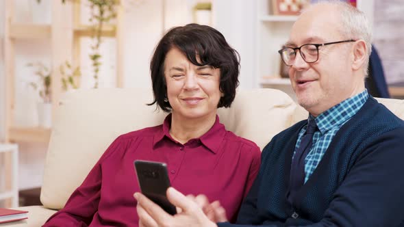 Happy Senior Couple Having a Video Call Seated on Couch in Their Living Room