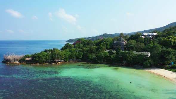 Wide angle above tourism shot of a white paradise beach and blue ocean background in vibrant 4K