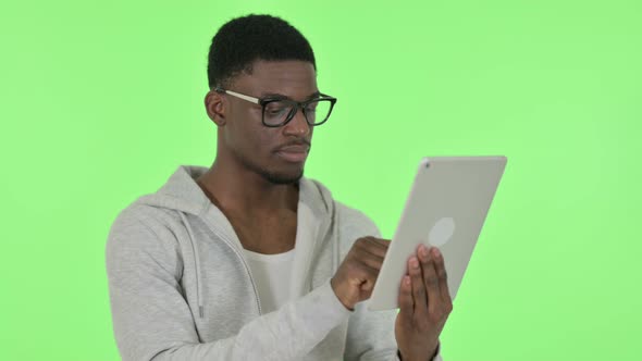 African Man Using Digital Tablet on Green Background