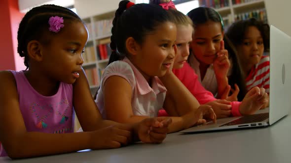 Schoolkids studying together on laptop at table 4k