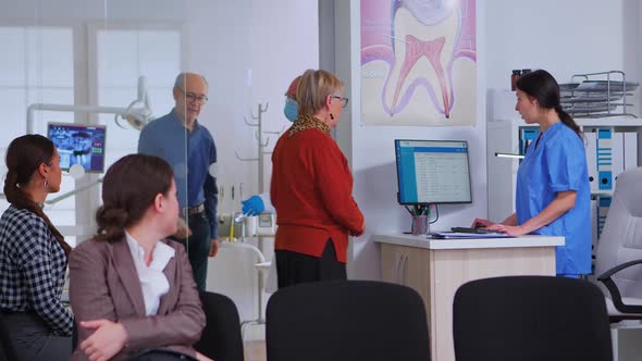 Dentistry Doctor Talking with Senior Woman Standing in Reception Area