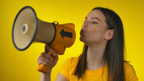 Shocked Young Woman in Casual Yellow Shirt Talking with Megaphone and Laughing