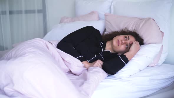 Portrait of Young Woman Closing Ears with Pillow in the Morning. Caucasian Girl Waking Up Because of