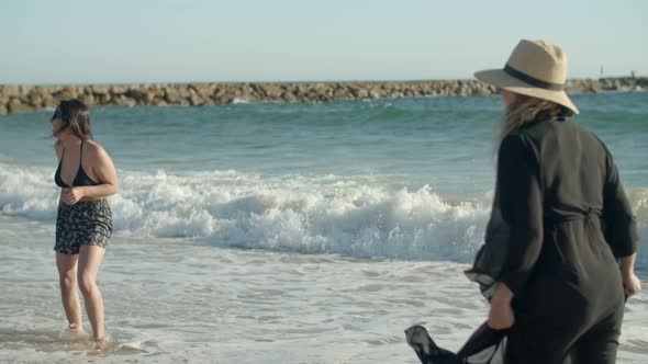 Long Shot of Family Standing on Beach and Splashing in Sea