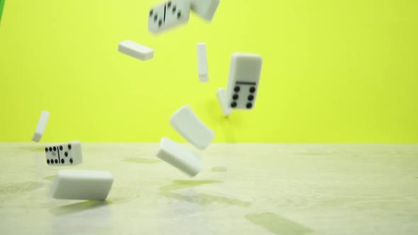 Slow Motion Shot of White Dominoes Fall on a Yellow Background