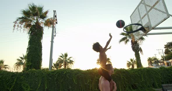 Father and Son of Different Nationalities Play Basketball the Child Sits on His Shoulders and