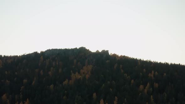 Aerial View of a Cliff Surrounded By a Colorful Autumn Forest at Sunset