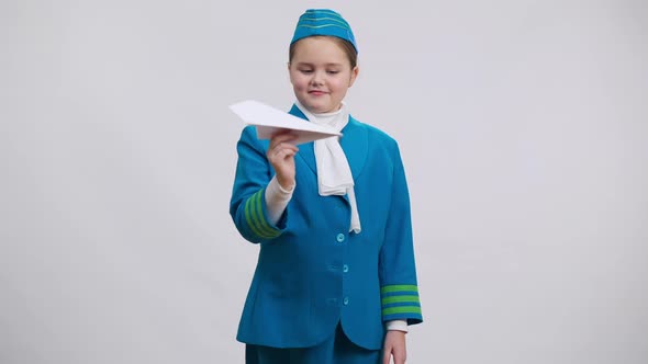 Cute Girl in Air Hostess Uniform Playing Landing Paper Plane Turning to Camera Smiling