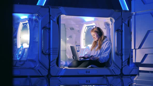 Box of a Capsule Hotel with a Girl Listening to Music Inside