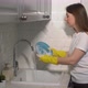 Young Woman in Yellow Rubber Gloves in the Kitchen is Washing Dishes By Hand - VideoHive Item for Sale
