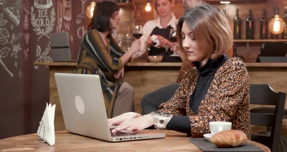 Young Business Woman Typing an Important Message on Her Laptop While in a Coffe Shop