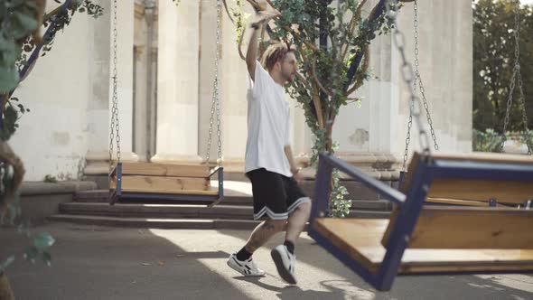 Wide Shot Dance of Confident Smiling Young Man in Sunglasses Outdoors