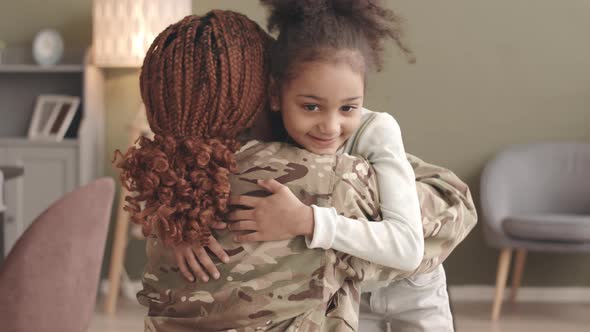 Woman in Military Uniform Embracing Little Daughter alt