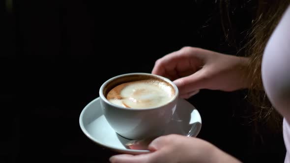 Closeup of Cup of Black Coffee and Saucer in Female Hands