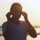 Woman is Putting Earphones to Listen Music Before Jogging on the Sea Beach - VideoHive Item for Sale