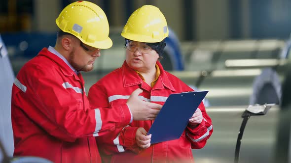 Two Workers in Production Plant As Team Discussing Industrial Scene in Background