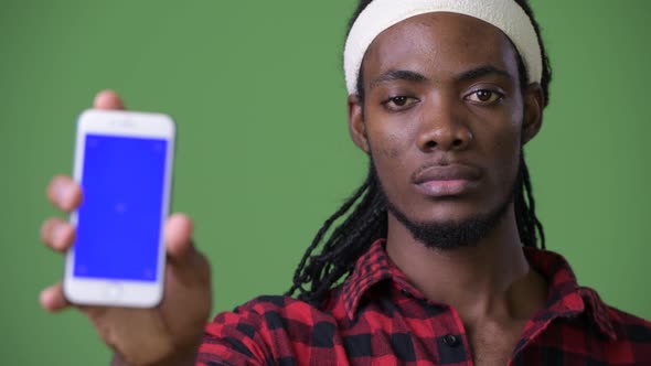 Young Handsome African Man with Dreadlocks Against Green Background