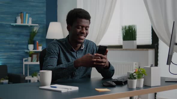 Positive Authentic Black African American Man Smiling While Using a Smartphone
