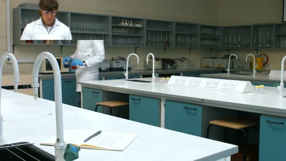 Scientist with sample of red and blue chemical writing his notes