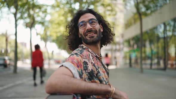 Pleased curly-haired bearded man in eyeglasses looking around
