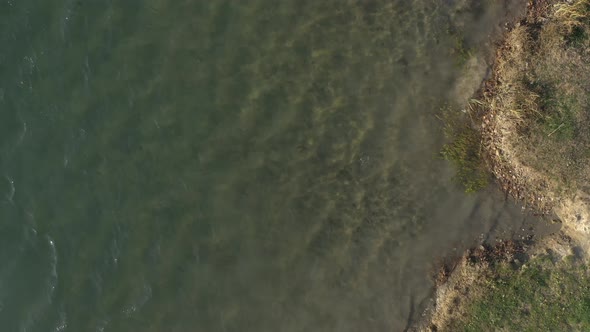 Descending over shallow lake waters 4K aerial footage