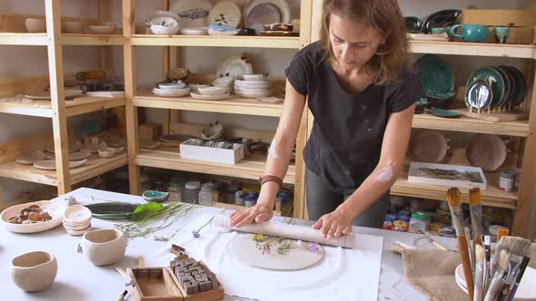 Female Sculptor Creates an Original Drawing of Flowers on a Clay Blank.