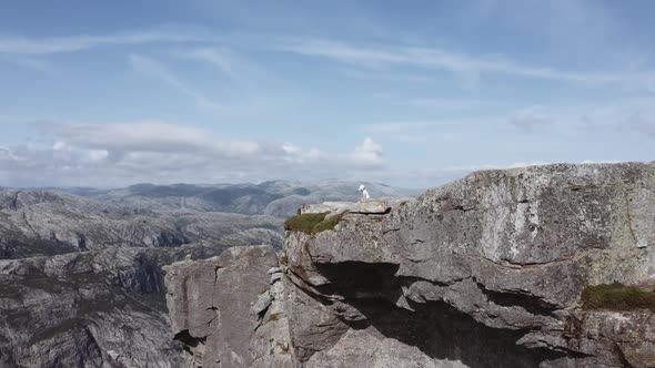 Pan Shot of a Tourist Sitting and Admiring the View at Pulpit Rock Norway