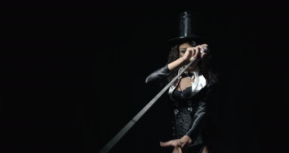 Magician Woman in Black Suit and Top Hat Is Swinging Her Cane Around Film Grain