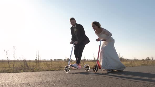 Young Couple Ride a Scooter in Road at Sunset