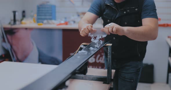 Master Scrapes the Wax From the Ski with a Scraper