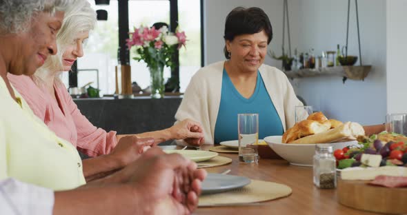 Happy senior diverse people praying before dinner at retirement home