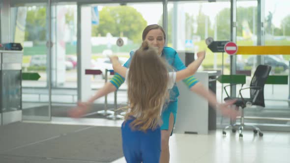 Cheerful Little Girl Meeting Mother Stewardess in Airport. Back View of Happy Caucasian Child